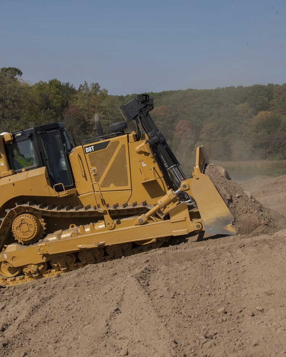 Caterpillar D8T dozer pushing soil with grade-control hardware on an active construction site