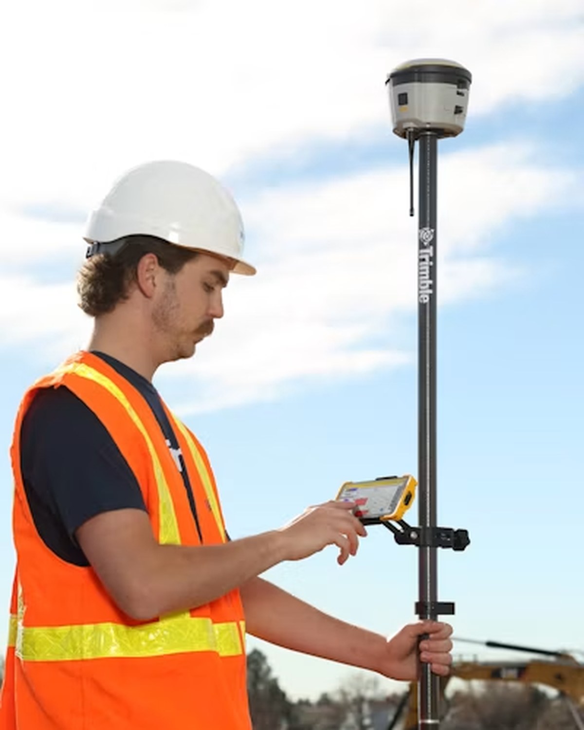 Construction worker using a Trimble GNSS rover and field controller on a jobsite