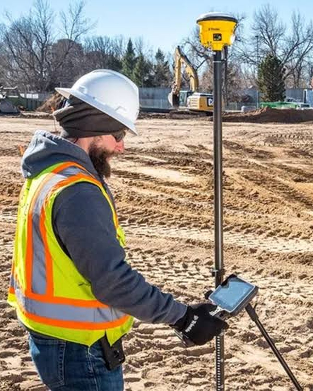 Construction worker checking grade with a Trimble GNSS rover and field controller