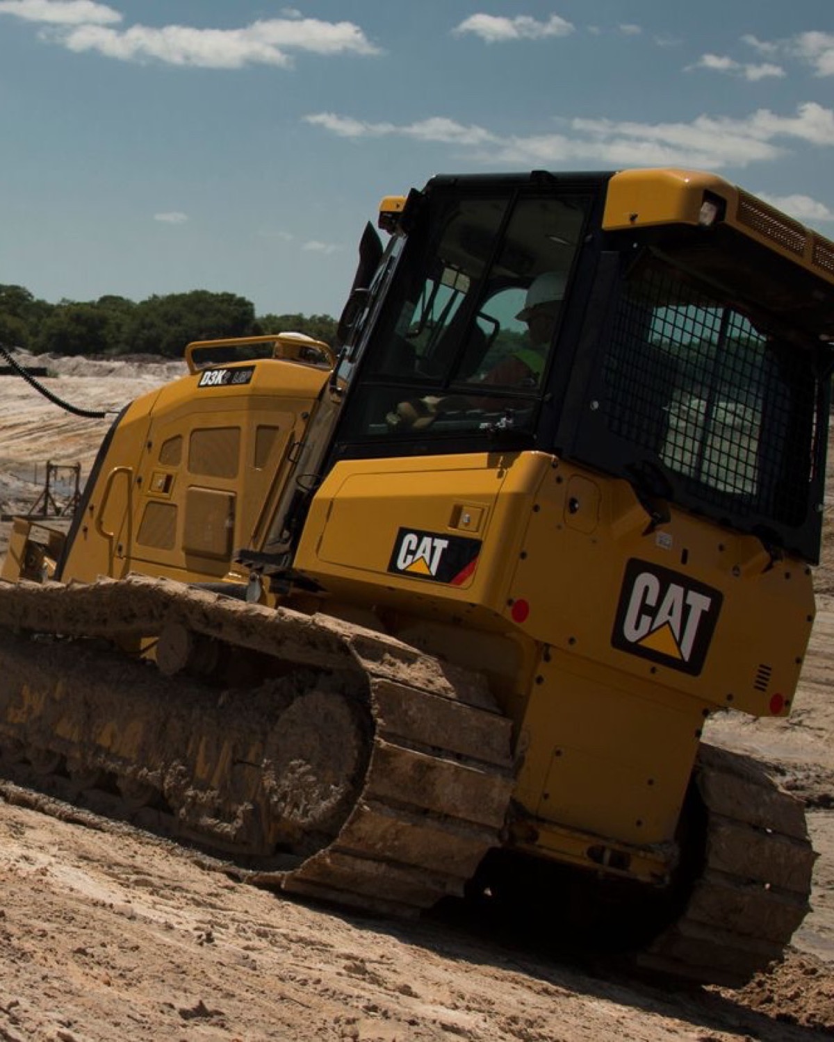 Caterpillar D3K dozer operating with mounted grade-control hardware on sloped earthwork